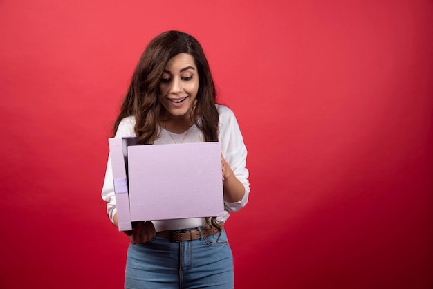 Hermosa mujer mirando dentro de la caja presente púrpura. Foto de alta calidad