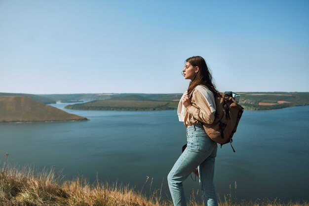 Hermosa mujer con mochila en la colina cerca del río dniéster