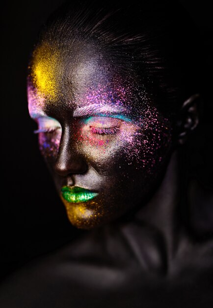 Hermosa mujer modelo con plástico negro creativo máscara negra inusual maquillaje colorido brillante con cara negra