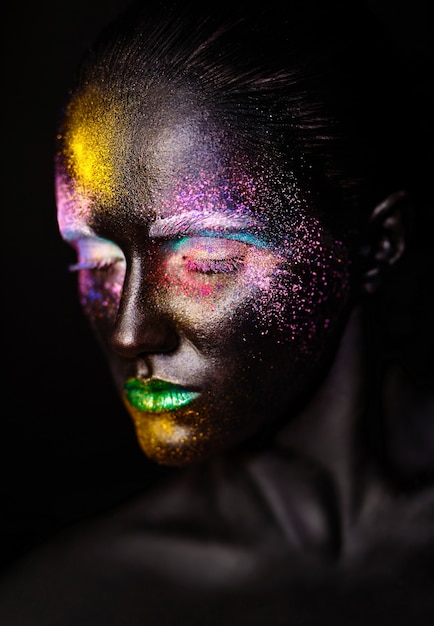 Hermosa mujer modelo con plástico negro creativo máscara negra inusual maquillaje colorido brillante con cara negra
