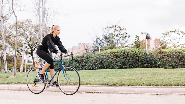 Foto gratuita hermosa mujer montando bicicleta en el parque