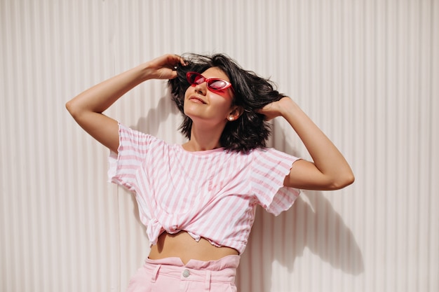 Hermosa mujer morena disfrutando de día de verano. Mujer hermosa en gafas de sol posando sobre fondo de textura.