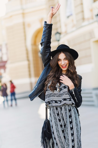 Foto gratuita hermosa mujer morena increíble con largo peinado ondulado en primavera u otoño elegante traje urbano caminando por la calle. labios rojos, cuerpo delgado. concepto de moda callejera.