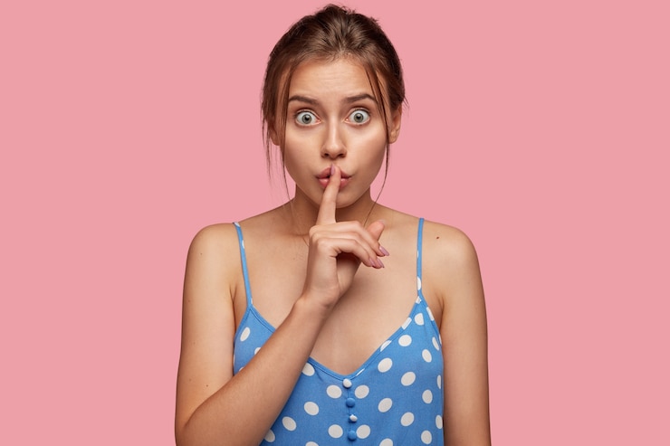 Foto gratuito hermosa mujer morena sorprendida mantiene el dedo índice sobre la boca