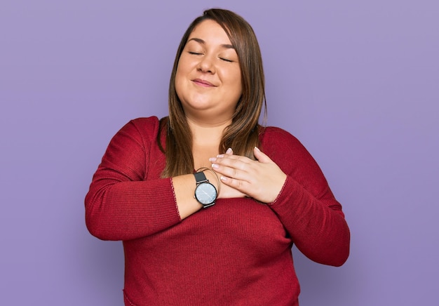 Hermosa mujer morena de talla grande con ropa informal sonriendo con las manos en el pecho con los ojos cerrados y un gesto agradecido en el concepto de salud facial