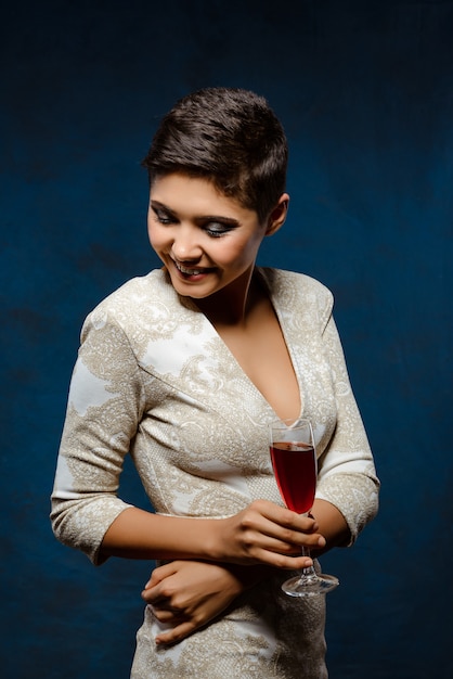 Hermosa mujer morena en vestido de noche sonriendo, sosteniendo una copa de vino