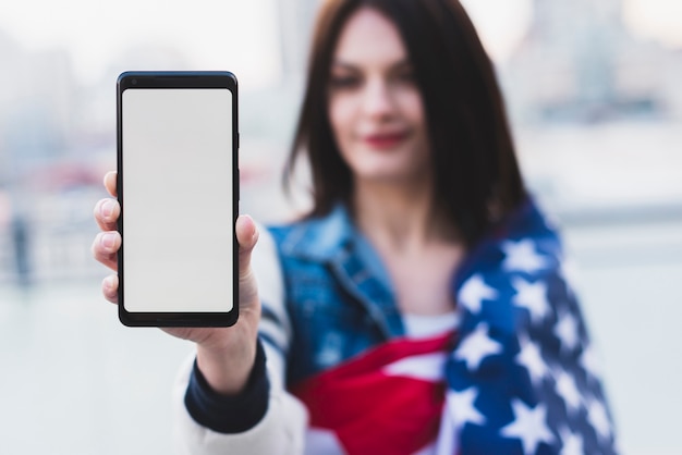 Hermosa mujer mostrando teléfono con pantalla blanca