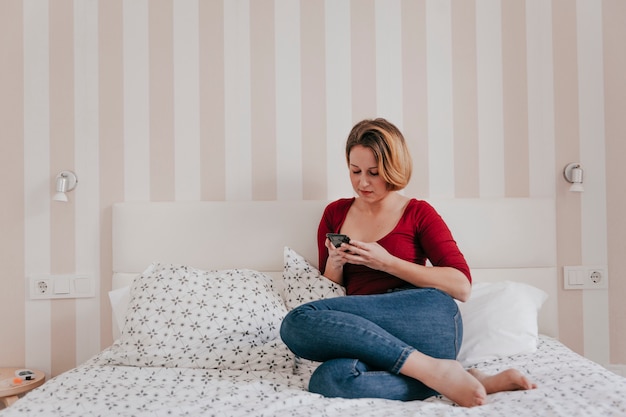 Hermosa mujer navegación smartphone en la cama