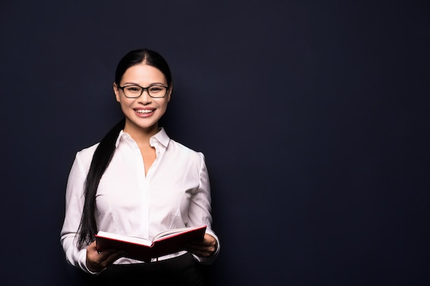 Hermosa mujer de negocios asiática sonriendo a la cámara y sosteniendo el cuaderno