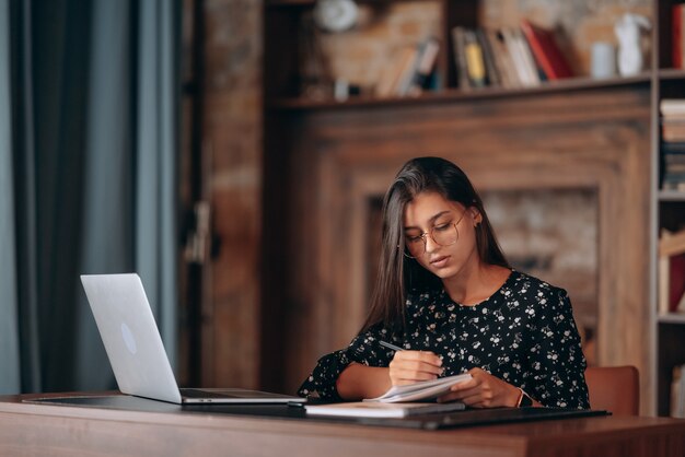 Hermosa mujer de negocios escribiendo algo en el cuaderno