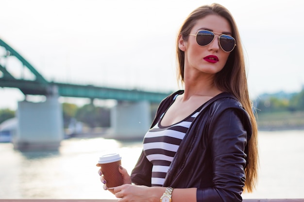 Foto gratuita hermosa mujer de negocios ocasional, chica con café en la puesta de sol río.