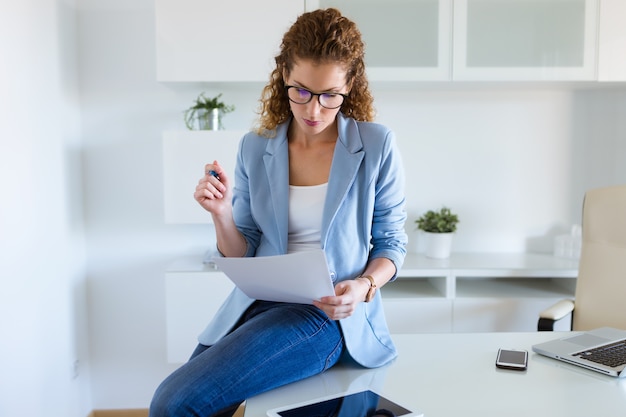 Hermosa mujer de negocios revisando documentos en la oficina.