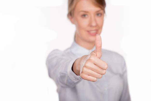 Hermosa mujer de negocios sonriente de pie contra el fondo blanco. Pulgar arriba.