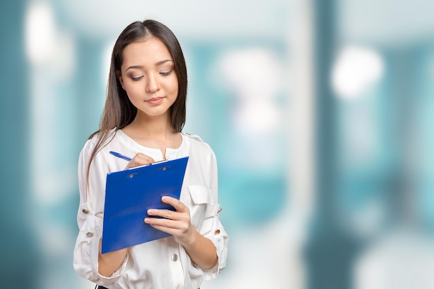 Hermosa mujer de negocios tomando notas en su portapapeles