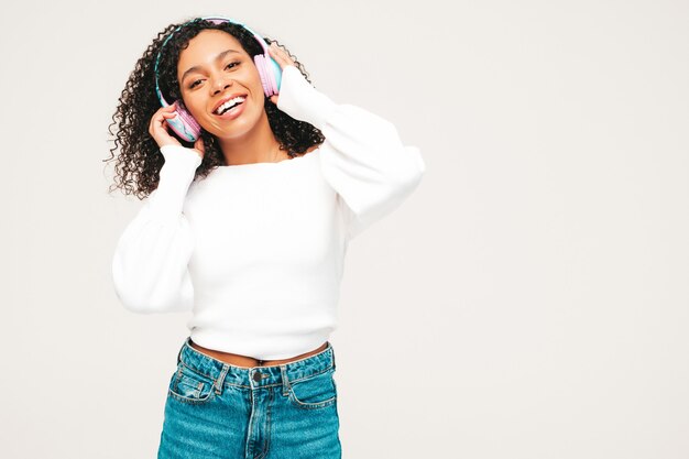 Hermosa mujer negra con peinado afro rizos. Modelo sonriente en suéter y jeans