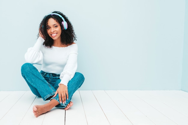 Hermosa mujer negra con peinado afro rizos. Modelo sonriente en suéter y jeans