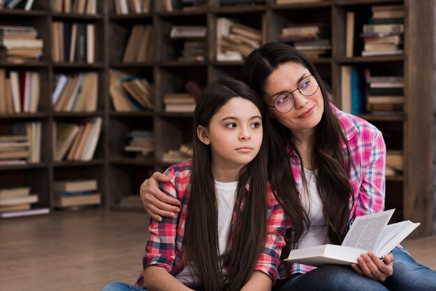 Hermosa mujer y niña en la biblioteca