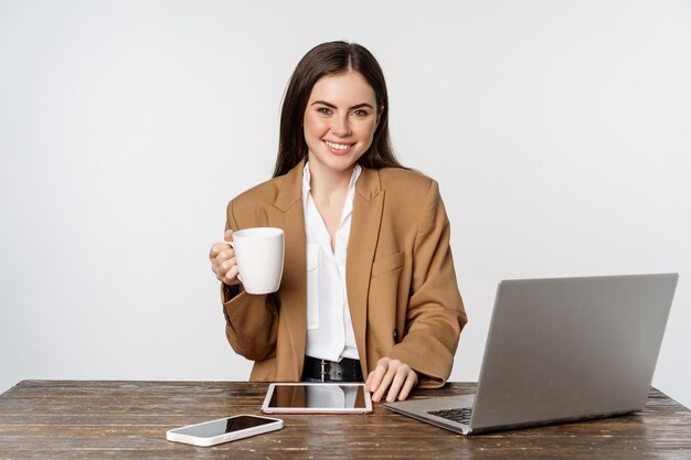 Hermosa mujer de oficina feliz mujer de negocios tomando café en el trabajo sentado en la mesa y sonriendo súplica...