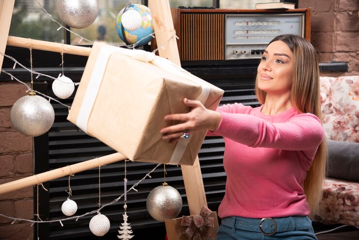 Foto gratuito hermosa mujer ofreciendo caja de regalo en casa