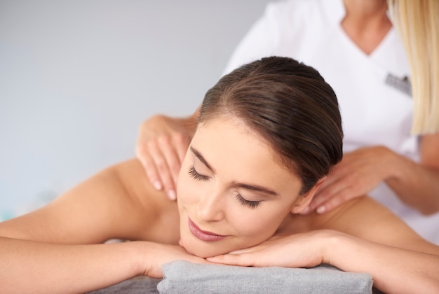 Hermosa mujer con los ojos cerrados durante el masaje de espalda