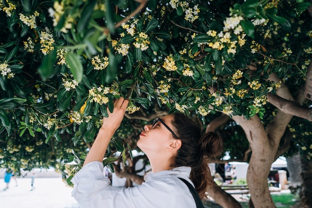 Hermosa mujer oliendo las flores de los árboles. tiempo de primavera