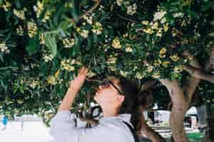 Foto gratuita hermosa mujer oliendo las flores de los árboles. tiempo de primavera