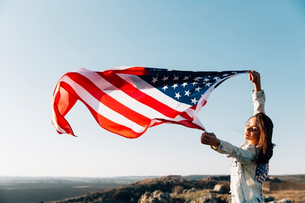 Hermosa mujer patriótica con banderas americanas revoloteando