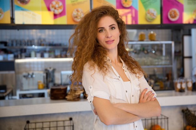 Hermosa mujer pelirroja barista mirando a cámara y sonriendo