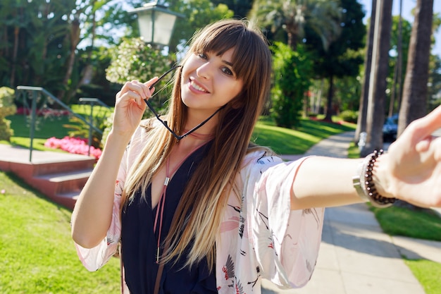 Foto gratuita hermosa mujer de pelo largo con peinado de moda haciendo autorretrato