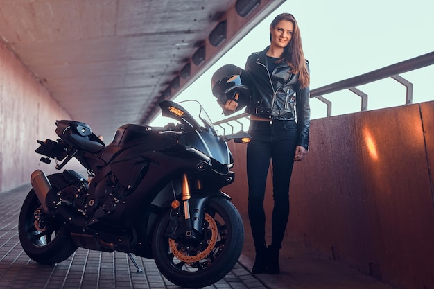 Hermosa mujer pensativa está parada en un túnel con su bicicleta y su casco.