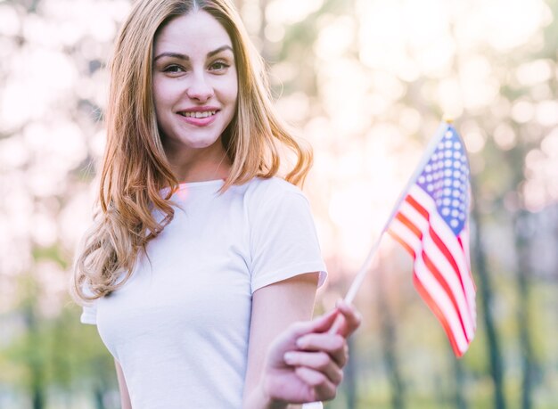 Hermosa mujer con pequeña bandera americana al aire libre