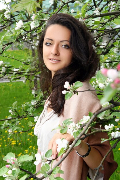 Hermosa mujer de pie por árbol floreciente