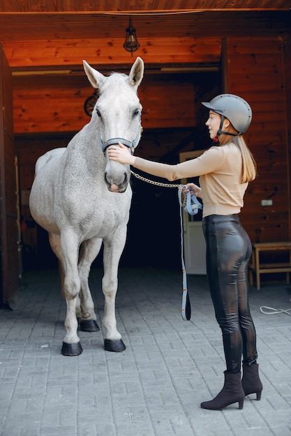 Hermosa mujer de pie con un caballo