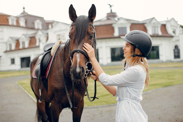 Hermosa mujer de pie con un caballo