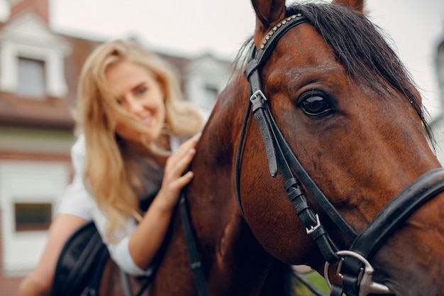 Hermosa mujer de pie con un caballo