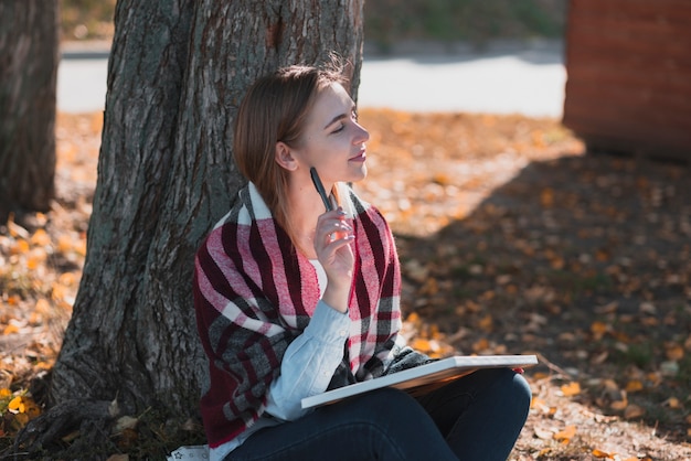 Hermosa mujer de pie cerca de un árbol