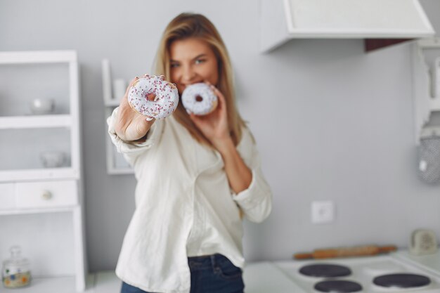 Hermosa mujer de pie en una cocina con donut