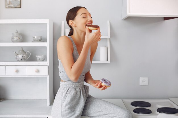 Hermosa mujer de pie en una cocina con donut