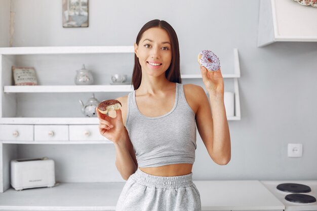 Hermosa mujer de pie en una cocina con donut