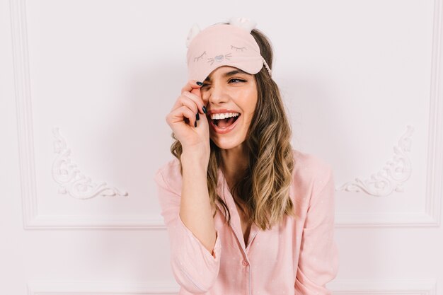 Hermosa mujer en pijama rosa posando en la pared