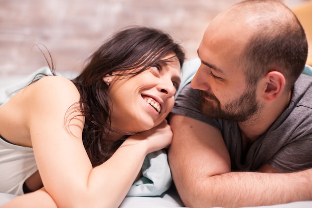 Hermosa mujer en pijama sonriendo mientras mira a su marido.