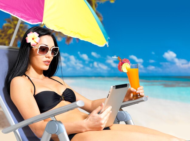 Hermosa mujer en la playa con ipad.