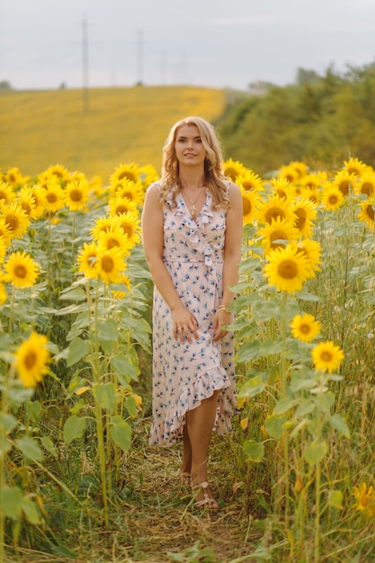 Hermosa mujer posa en el campo agrícola con girasol en un día soleado de verano