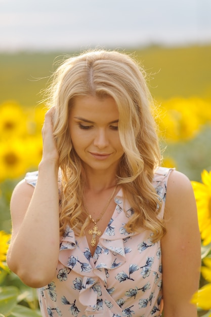 Hermosa mujer posa en el campo agrícola con girasol en un día soleado de verano