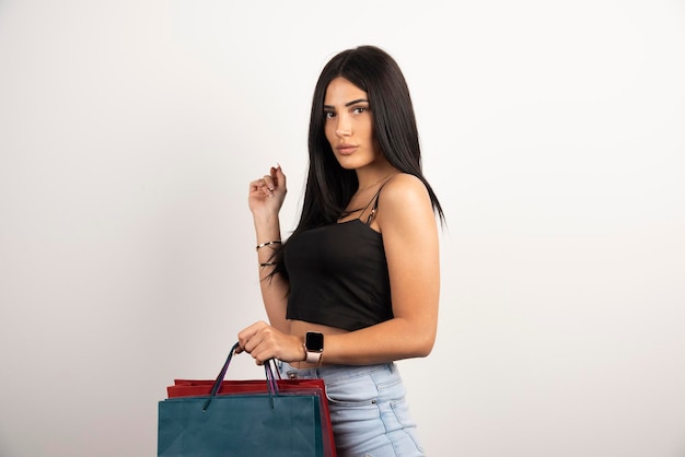 Hermosa mujer posando con bolsas de la compra sobre fondo beige. Foto de alta calidad