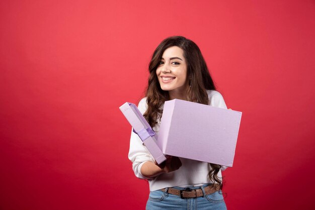 Hermosa mujer posando con caja de regalo púrpura. Foto de alta calidad