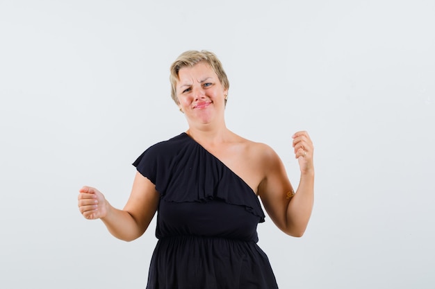 Foto gratuita hermosa mujer posando como sosteniendo algo en blusa negra y luciendo disgustada.