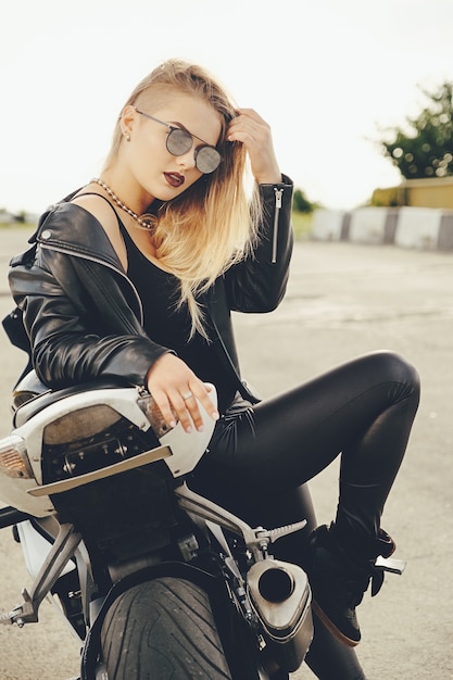 Hermosa mujer posando con gafas de sol en una moto