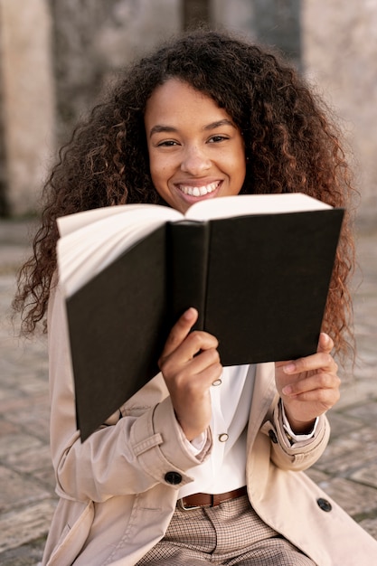 Foto gratuita hermosa mujer posando con un libro en la mano al aire libre