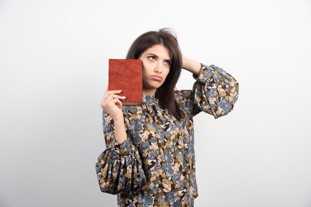 Hermosa mujer posando con libro sobre fondo blanco.